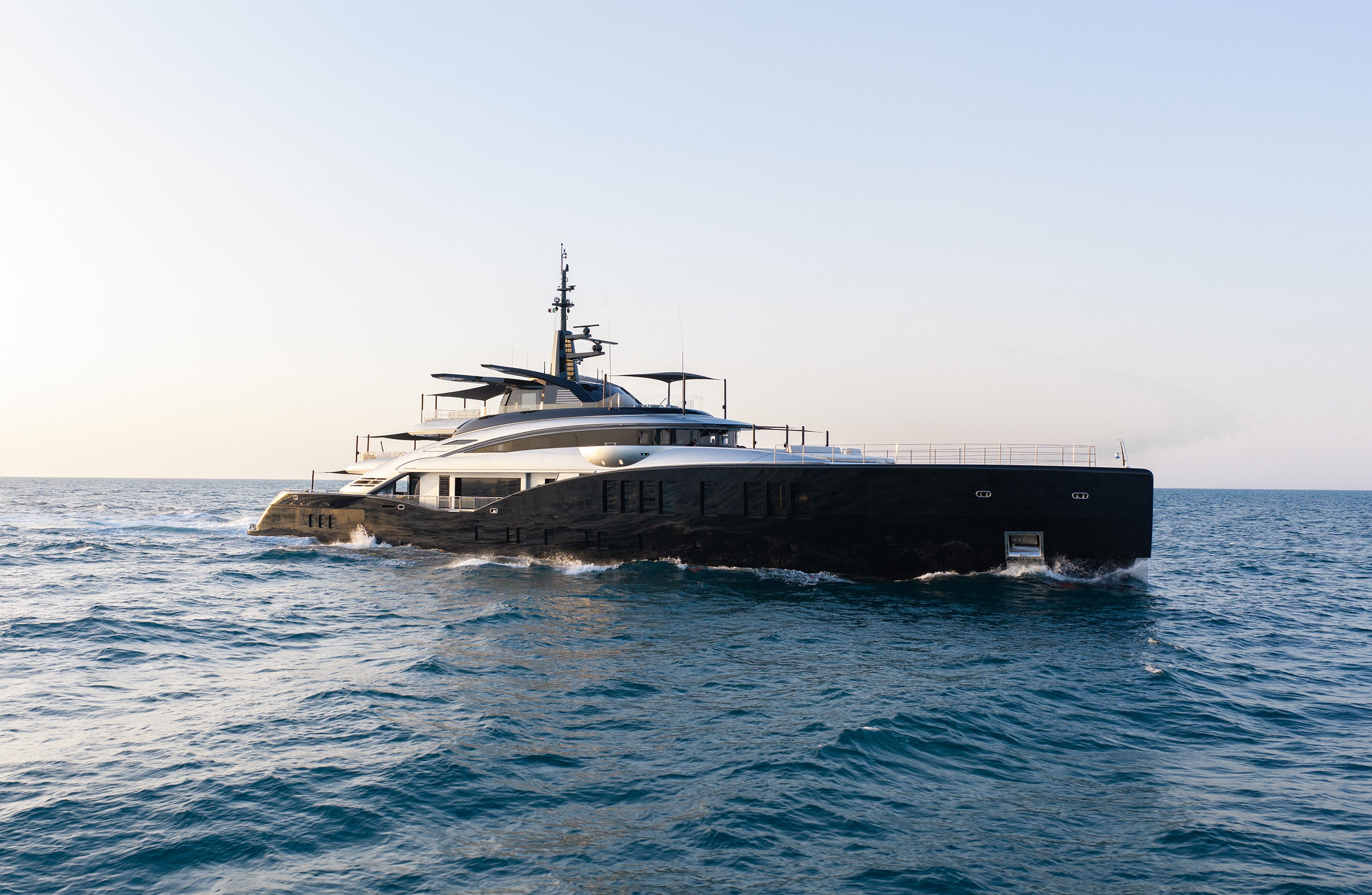 A photograph of Sea Raider X broadside on calm water, the full length of the black hull and the silver deckhouse above it