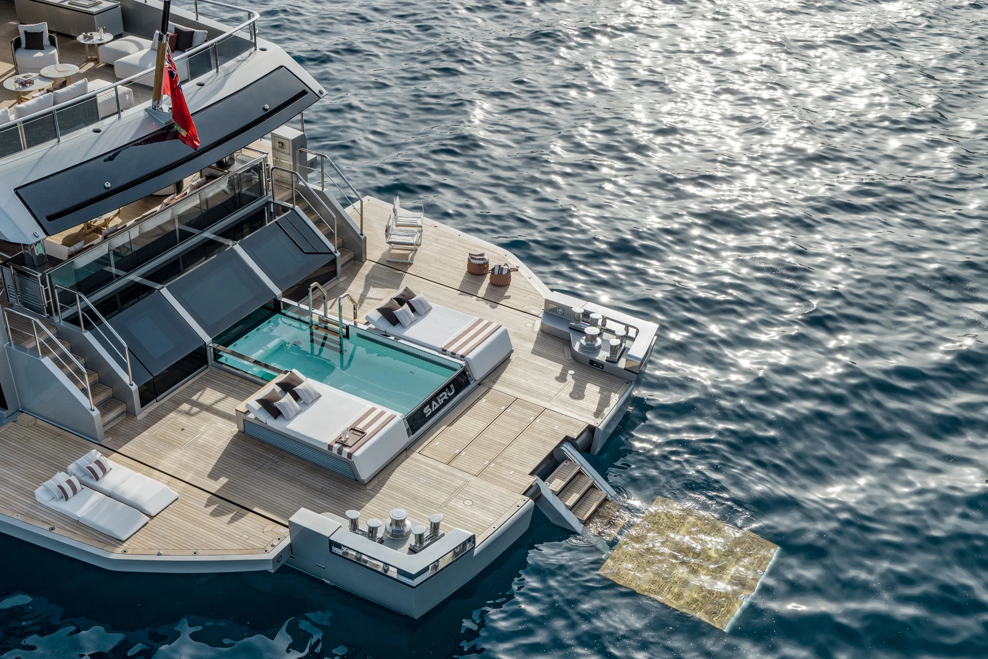 An aerial photograph looking down on the aft deck, a pool lettered SAIRU between two day beds and a swim platform lowered to the water