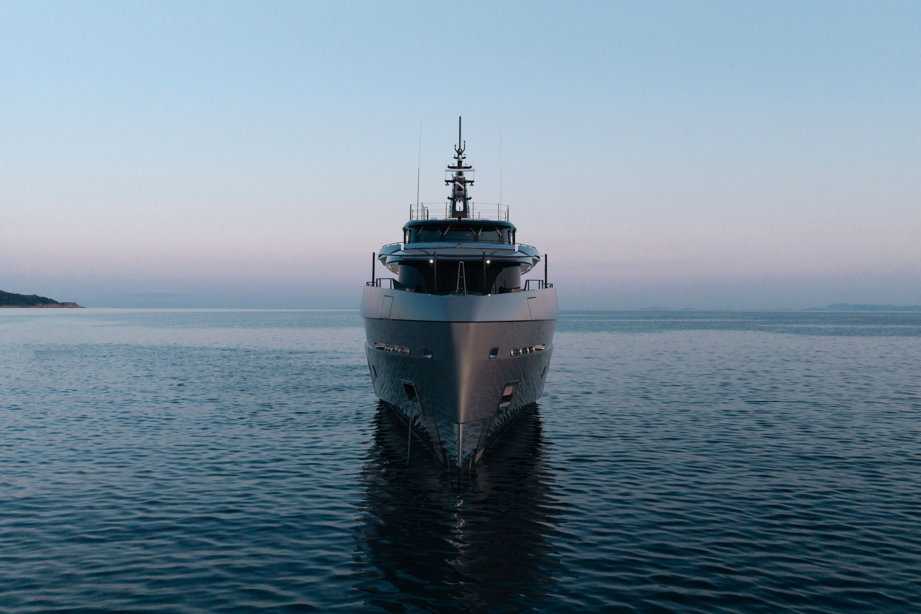 HEED head-on at dawn, a near-plumb bow and a narrow, stepped superstructure rising to the mast