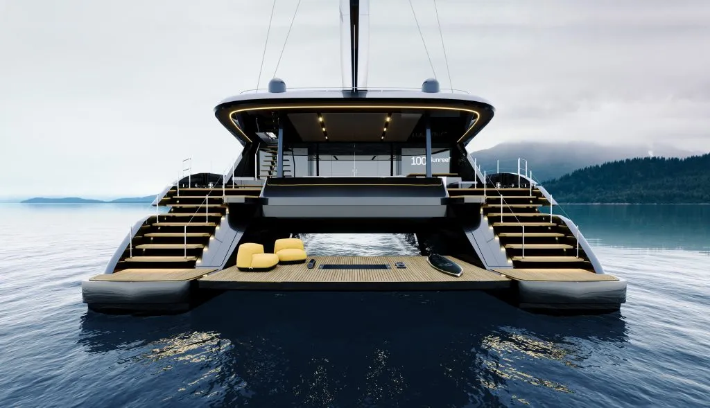 The stern of a Sunreef 100 Eco head-on, a wide teak beach platform between the hulls under a lit overhang