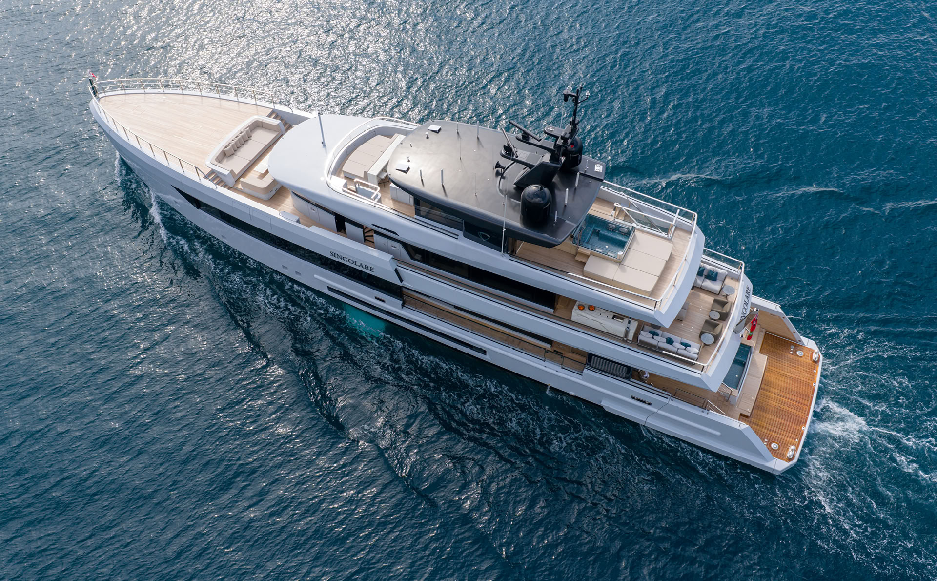An aerial photograph of Singolare under way seen from above and ahead, the long foredeck, the sun deck pool and the aft decks stepping down