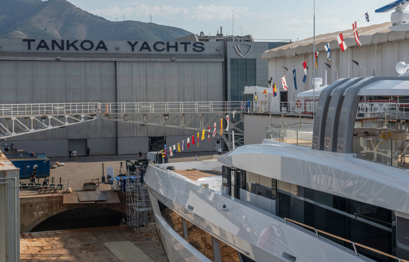 A photograph over Spirit's upper deck towards the Tankoa Yachts building, signal flags strung along the deck